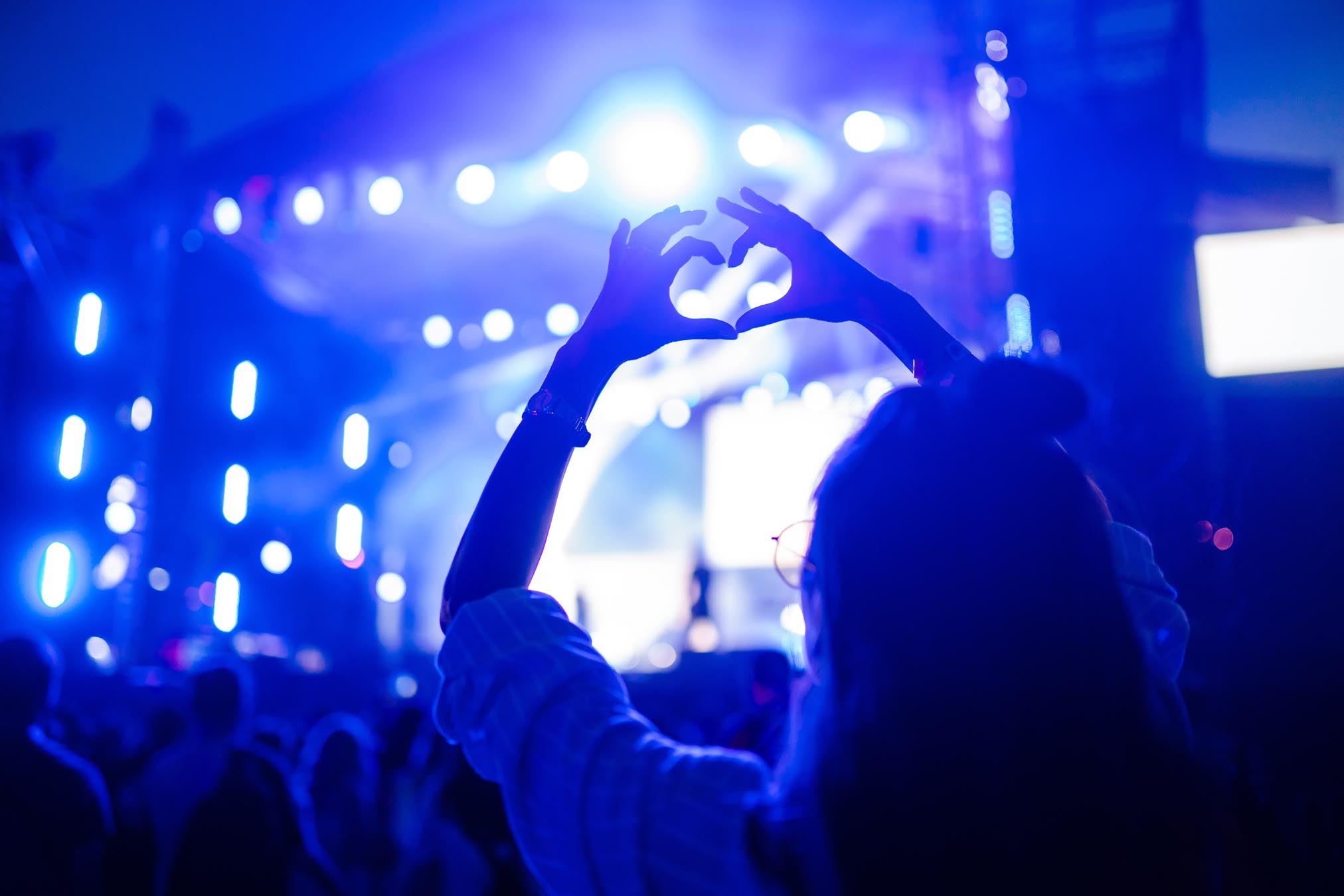 Woman making hands into heart at concert